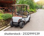 A white golf cart is parked on the street.