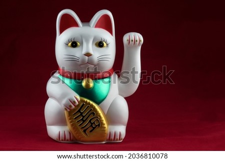 White good fortune waving cat isolated on a mottled red background