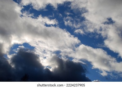 White gray cumulus clouds. Autumn day low fluffy clouds float across the sky. They are snow-white above and dark almost black below due to sunlight and cloud density. Behind them is a blue sky. - Shutterstock ID 2224237905
