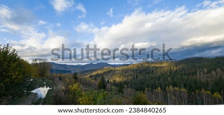 White and gray cumulus, stratus, cirrus clouds over the mountains. Autumn nature, yellow leaves on the trees. Panorama of the majestic mountains. Real nature.