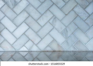 White And Gray Herringbone Italian Marble Tile In A Kitchen As A Backsplash With The Reflection On The Granite Countertop