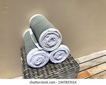 White With A Gray Stripe Towels Rolled Into A Roll In The Spa On A Wicker Cabinet On A Beige Background