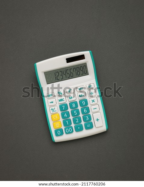 White and green\
calculator on a dark gray background. A device for computing.\
Minimal accounting\
concept.