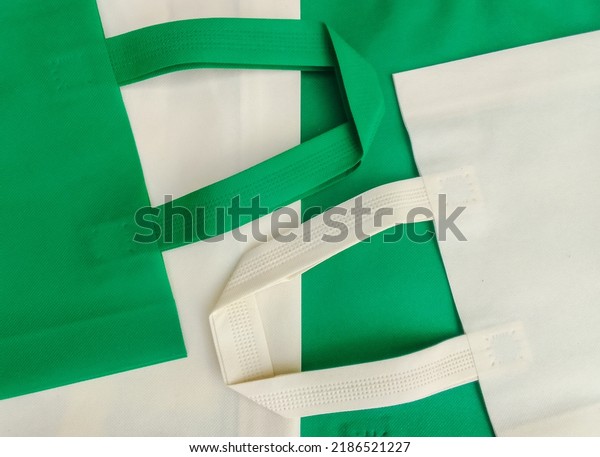white and green non woven cloth\
tote bag. a composition made of non-woven textile fabrics of pastel\
colors. porous polypropylene spunbond pile. partially\
sighted