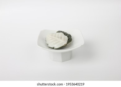 White and green rice cake in a dish isolated on white background