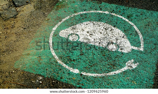White and green symbol of electric car charging,
on asphalt