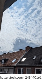 White and grey clouds of different shapes above the house