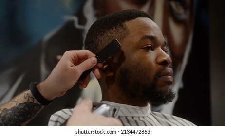 White guy doing a haircut to a young joyful african american guy in a beautiful barbershop - Powered by Shutterstock
