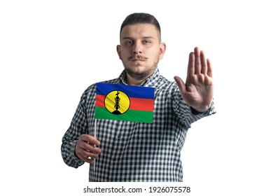 White Guy Holding A Flag Of New Caledonia And With A Serious Face Shows A Hand Stop Sign Isolated On A White Background.