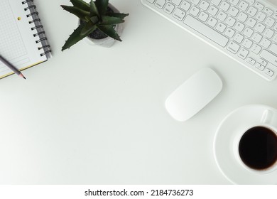 White GWERTY keyboard with a mouse and a cup of coffee on the white table surface. Working place concept. Flat lay of office desk. Copy space for a text. Telework concept