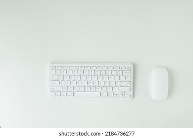 White GWERTY Keyboard And Mouse On The White Table Surface. Working Place Concept. Flat Lay Of Office Desk. Copy Space For A Text