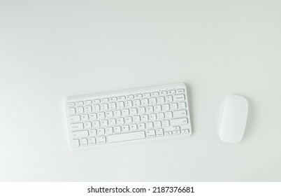 White GWERTY Keyboard And Mouse On The White Table Surface. Working Place Concept. Flat Lay Of Office Desk. Copy Space For A Text