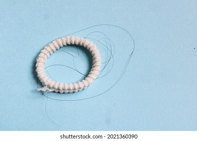 White Hairband With Stuck Hair Against Bluish Background Selective Focus