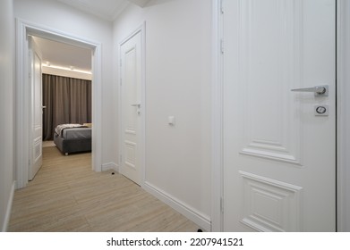 White Hallway, Door Is Open To A Bedroom With A Bed In The Background