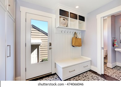 White hallway storage cabinet with hangers, bench with drawers and storage units on the top. And door to the bathroom . Northwest, USA