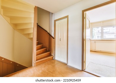 White Hallway With Wooden Stairway Leading To Second Floor Of Modern Luxury Apartment With Minimalist Interior Design