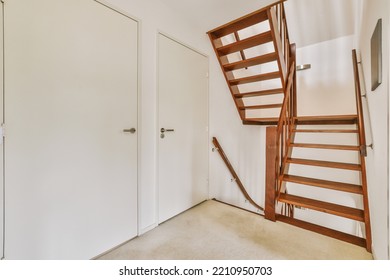 White Hallway With Wooden Stairway Leading To Second Floor Of Modern Luxury Apartment With Minimalist Interior Design