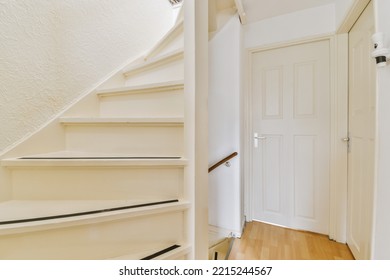 White Hallway With Wooden Stairway Leading To Second Floor Of Modern Luxury Apartment With Minimalist Interior Design