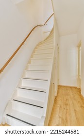 White Hallway With Wooden Stairway Leading To Second Floor Of Modern Luxury Apartment With Minimalist Interior Design