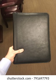 White Hand Holding Black Leather Portfolio