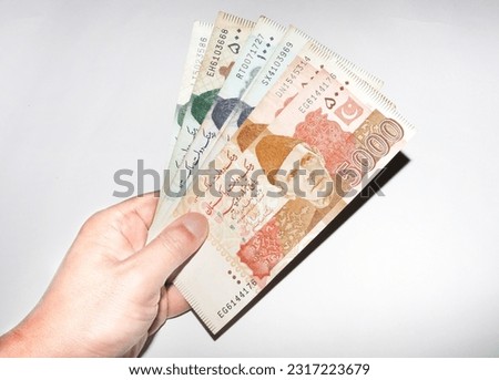 white hand holding Pakistani currency banknotes on white background. Multiplr currencey  banknotes