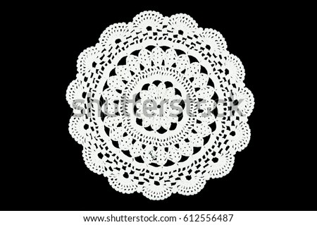 White hand made crocheted coaster lace doily on black background. 