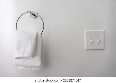 White Hand Towel And Light Switch With White Wall.