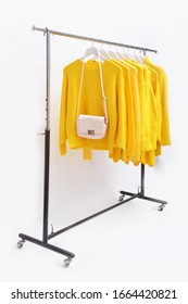 White Handbag With Collection Of Yellow Color Different Yellow Clothes ,coat, Sweater, Shirt ,sundress ,jacket Hanging On Wooden Clothes Hanger In Closet Or Clothing Rack Over White Background


