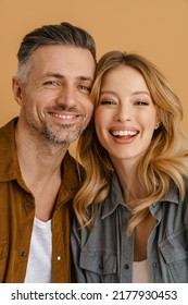 White happy couple wearing shirts smiling and looking at camera isolated over beige background - Shutterstock ID 2177930453