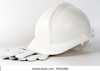 white hard hat and protection gloves on background