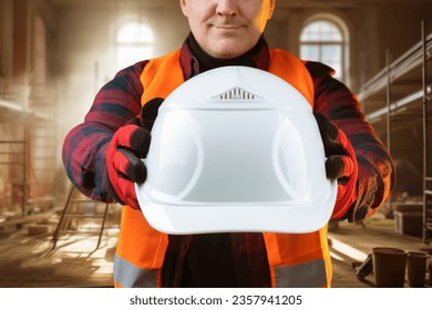 White hardhat in builder hand. Protective helmet for worker head. Foreman recommends wearing hardhat. Master in renovated room. Construction safety equipment. Cropped foreman with hardhat