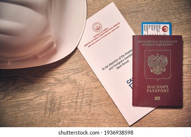 White Hardhat, Russian Foreign Passport And Turkish Work Permit At Wooden Desk Top Down View. Concept Of Foreign Work Permit Obtaining. Abroad Labor Migrations Concept. Flat Lay 