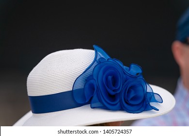 A White Hat With Blue Ribbon At A Horse Race.