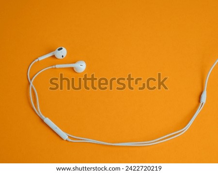 White headphones with cable on an orange background. Headphones close-up.