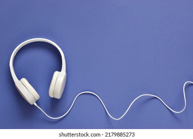 White headphones on a very peri purple background. Music concept. Music day. Flat lay composition with copy space 