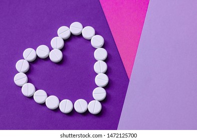 The White Heart Pills On A Colored Background. The Concept Of A Healthy Life. Heart Disease. Arrhythmia, Heart Failure. Health Problem. The Impact Of The Pill On Pregnancy. Copy Space.