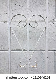 White Heart Shaped Wrought Iron Railing In Front Of A White Breeze Block Wall