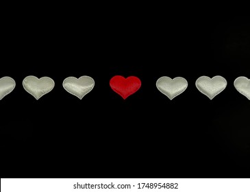 White hearts in a row with a central red heart on a black background. Concept: you are not like everyone else, special, true love. Blank for card with your text. Image with selective focus on the cent