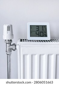 White heating radiator with thermostat and digital hygrometer at home, 31.0°C, 41%.