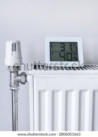 White heating radiator with thermostat and digital hygrometer at home, 31.0°C, 41%.