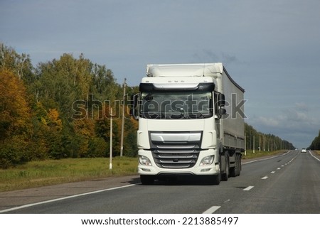 White heavy semi truck drive on countryside highway road front view at autumn day. Goods import in Europe