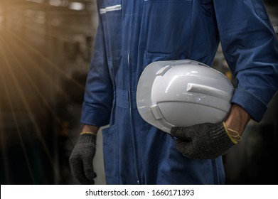 White helmet attached to the side of the factory technician. hand or arm of an engineer holding a white safety helmet, be prepared for work safety.