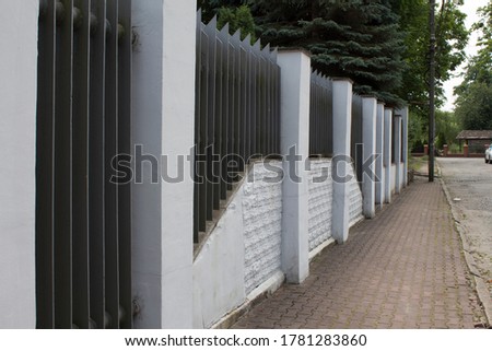 White high plastered fence with solid metal elements