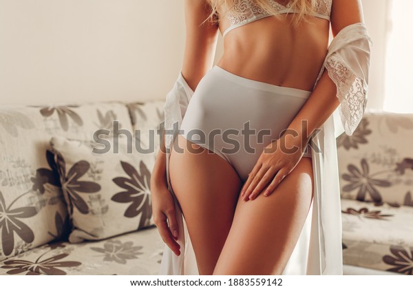 White high-waist panties on sportive booty and bra.\
Slim woman wearing sexy lace underwear and dressing gown at home.\
Healthy young female body