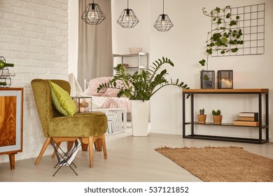 Wit interieur met groene fauteuil en bakstenen muur