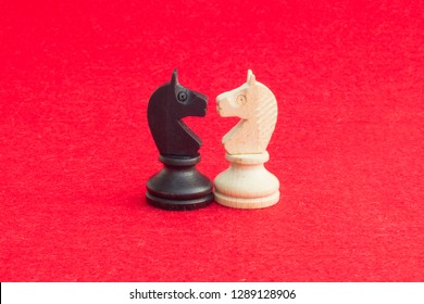 White horse and black horse, traditionally confronted in chess game, have reconciled. Image in isolated red background. - Powered by Shutterstock