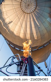 a white hot air balloon on during preparation for the launch is heated by a flame