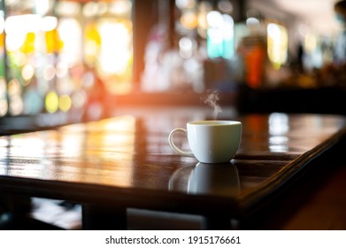 White hot coffee cup with steam on the table in blurred cafe background.Photo select focus. - Powered by Shutterstock