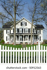 White house with black shutters and white picket fence