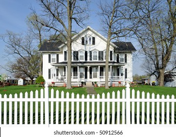 White house with black shutters and white picket fence